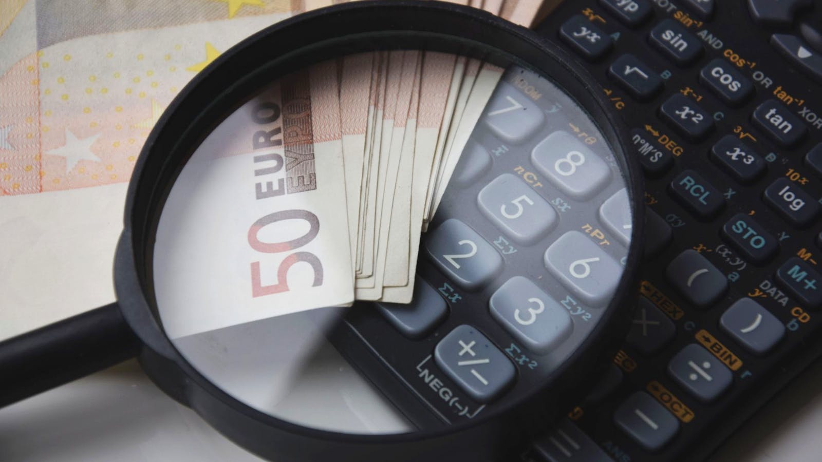 Billete de euro junto a una calculadora sobre un escritorio, como representación de precios en euros