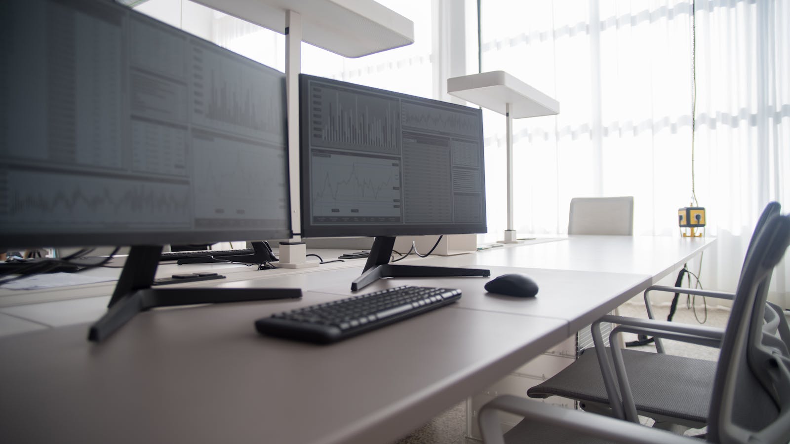 Espacio de trabajo de agencia moderno con dos monitores y un teclado sobre un escritorio despejado